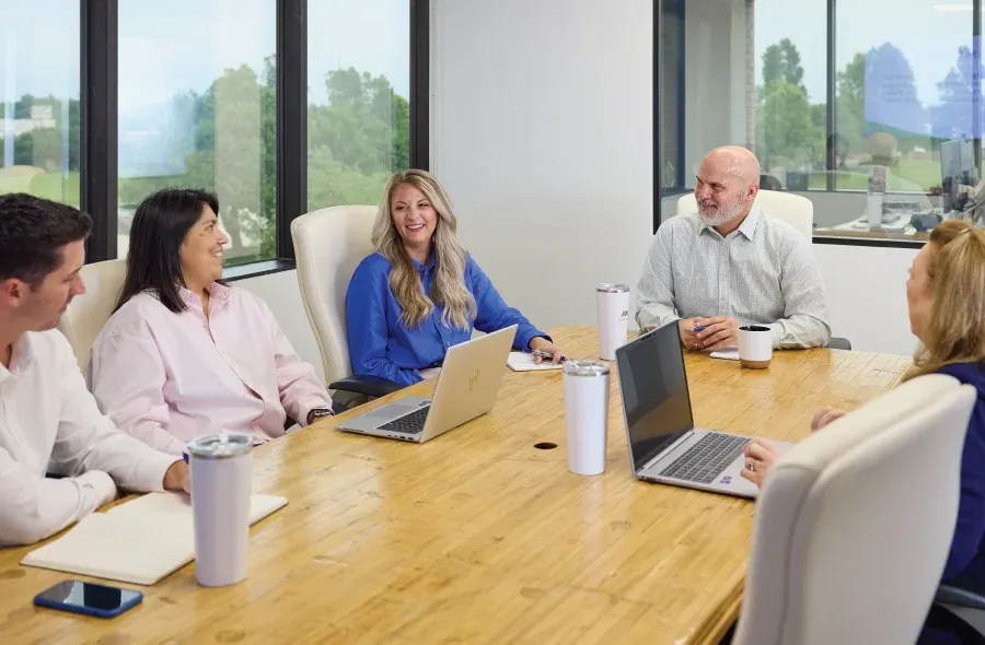 team gathered for a meeting, all members smiling